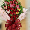 Tall bouquet of red roses with pink butterflies and a large red bow in pink wrap