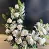 Tall crescent-shaped arrangement of white roses, lilies, and mums with green accents