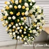Standing open-circle wreath of white and yellow flowers on an easel