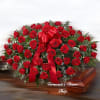 Red rose casket spray with a large red bow on a wooden casket