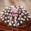 Pink rose casket spray with ribbon on a wooden casket