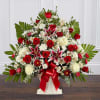 Large red and white flower arrangement with lilies and roses in a white urn with red ribbon