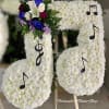 Standing floral tribute shaped like musical notes in white flowers with purple and blue accents