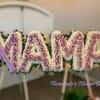 Standing floral tribute spelling MAMA with pink roses and white flowers on easels