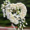Large white heart-shaped standing wreath with roses, lilies, orchids, and calla lilies