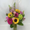Tall mixed arrangement with sunflowers, pink gerberas, roses, and green hydrangeas in a clear glass vase