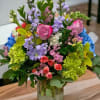 Colorful mixed bouquet with pink roses, orchids, hydrangeas and stock in a clear glass jar vase