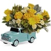 Yellow roses and white flowers arranged in a turquoise pickup truck container