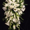 Cascading bouquet of white calla lilies, roses, and lisianthus against a black background