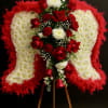 Standing sympathy arrangement of white angel wings with red roses on a wooden easel