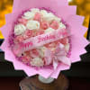 Round bouquet of pink and white roses with pink wrapping, birthday ribbon, and bow on a small pedestal stand