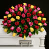 Multicolor rose casket spray of red, pink, and yellow roses on a white casket.