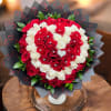 Red and white rose bouquet in black wrap with a white vase
