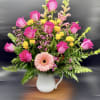 Pink roses and a peach gerbera daisy in a white pitcher vase