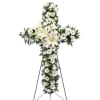 White floral cross on a stand with lilies and daisies