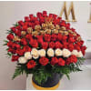 Large arrangement of red, gold, and white roses in a black hatbox
