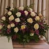 White roses and purple flowers arranged in a large funeral spray