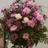 Pink and white floral arrangement with roses and daisies on a stand