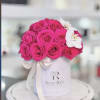 A stunning blend of vibrant fuchsia roses and elegant white orchids arranged