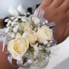 Creamy white roses clustered with baby's breath create an elegant wrist corsage