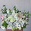 White floral arrangement with orchids and roses in a wooden box