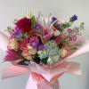 Pink and purple bouquet with roses, lilies, and hydrangea wrapped in pink paper