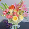 Bouquet of pink and yellow roses with pink lilies in a glass vase