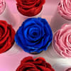 Top view of red, pink, and one blue rose displayed individually in small white cylinders