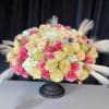 Round bouquet of pink, cream, and white roses in a black pedestal vase