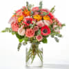 Bouquet of pink, coral, and yellow flowers in a clear glass vase