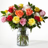 Mixed roses in pink, yellow, red, and peach arranged in a clear glass vase.