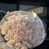 Bouquet of pale pink roses wrapped in white paper with gold trim