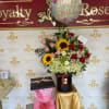 Birthday balloon above a mixed flower arrangement with roses and sunflowers