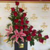 Tall arrangement of red roses and pink lilies in a black box