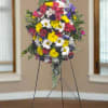 Standing floral spray with mixed bright flowers on a metal easel