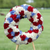 Circular wreath of red, white, and blue carnations on a stand