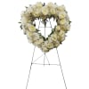 Heart-shaped white rose funeral wreath on a metal stand