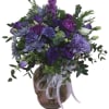 Purple floral arrangement in a round glass vase with a ribbon bow