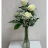 Three white roses in a clear glass vase with baby's breath