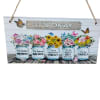 Decorative hanging sign with painted flower jars and the words "IT'S OKAY"