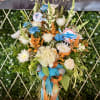 Tall bouquet of white and blue flowers in a glass vase with ribbon