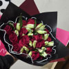 Bouquet of red roses and white lily buds wrapped in black paper