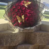 Large bouquet of red roses wrapped in black and white paper with gold butterfly accents