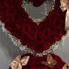 Heart-shaped red rose arrangement with baby’s breath and satin bows