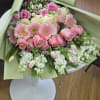 Large bouquet of pink roses, gerbera daisies, and white flowers wrapped in pale green paper