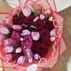 Bouquet of red roses and pink tulips wrapped in red paper