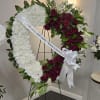 Heart-shaped funeral wreath of white chrysanthemums and red roses on an easel