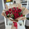 Bouquet of red roses wrapped in beige paper with a red ribbon