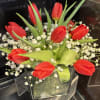 bright orange tulips on a short vase with baby&rsquo;s breath.