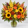 Bright mixed bouquet with sunflowers, roses, lilies, and chrysanthemums in a glass vase